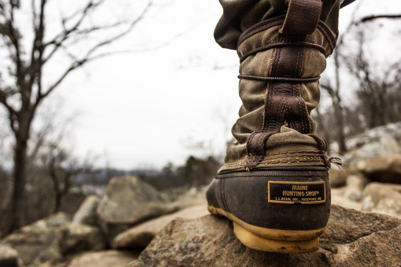 Close up of one trekking boot on a rock in the wild