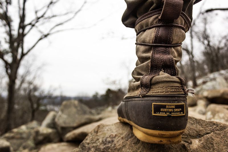 Close up of one trekking boot on a rock in the wild