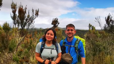 Arwa and Matias in hiking gear and smiling at the camera in the moorland section of Kilimanjaro