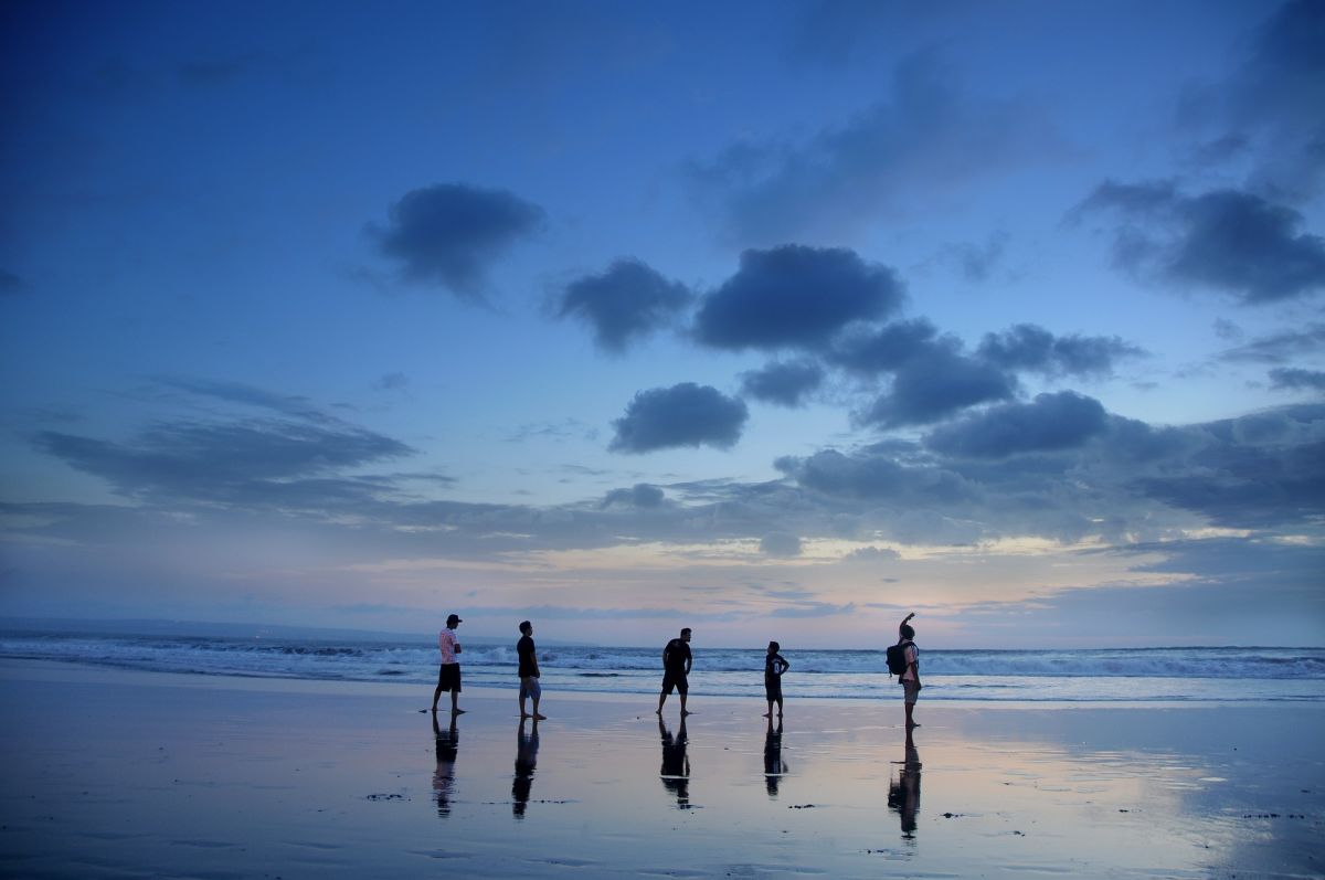 Bali. group of adults silhouetted against dim light on beach