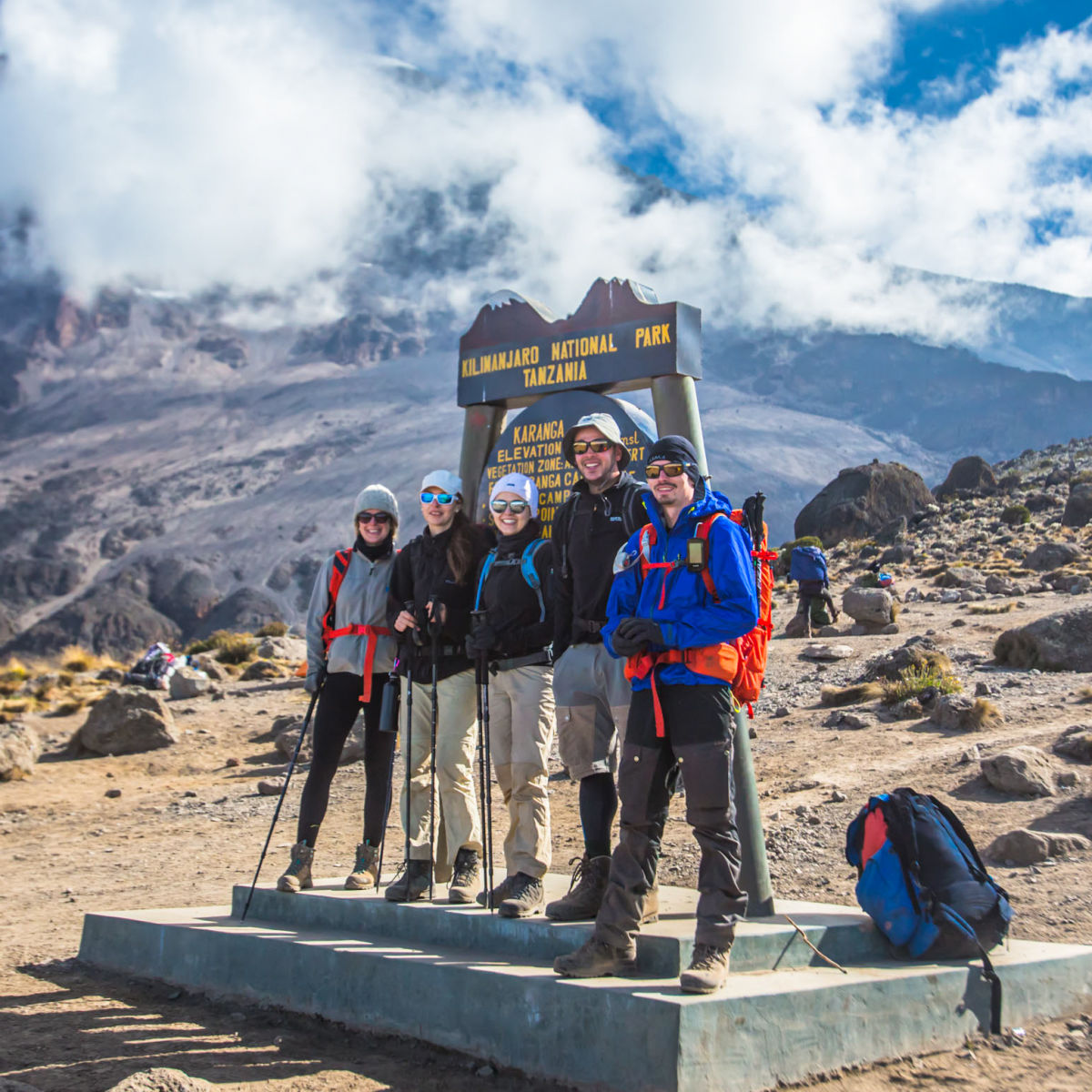 Smiling group of trekkers in front of Karanga Camp sign on Kilimanjaro
