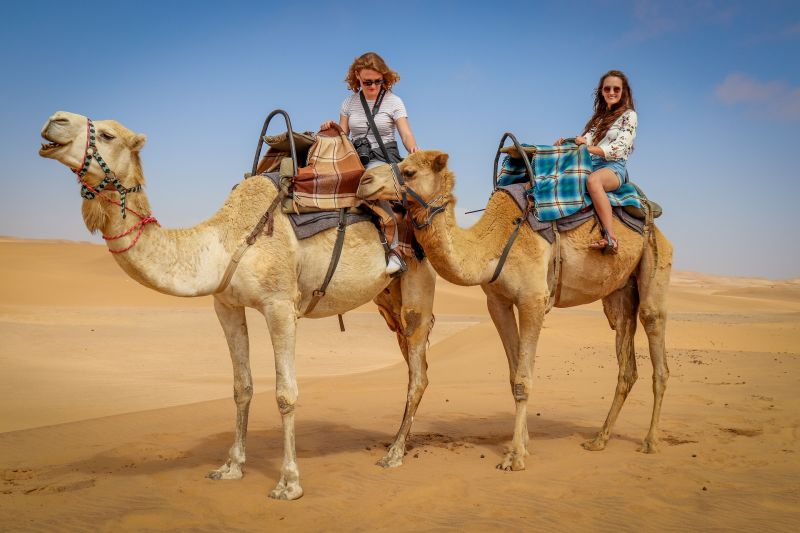 Two women on camels in the desert