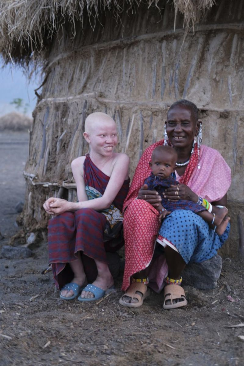 Maasai family portrait by thatched hut