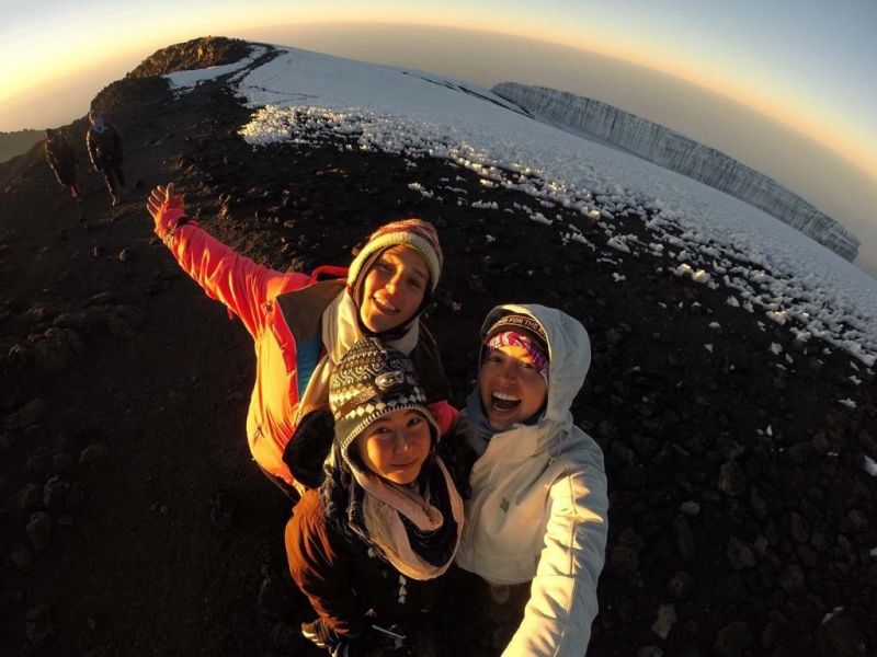 Three ladies taking a selfie at summit with glacier in background