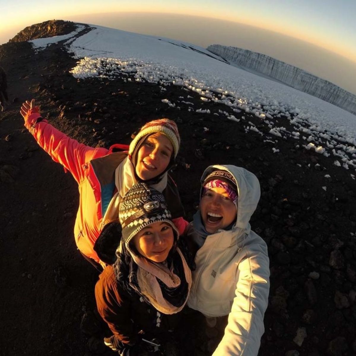 Three ladies taking a selfie at summit with glacier in background