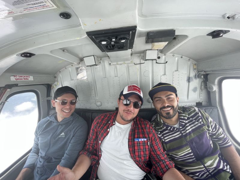 Three men smiling inside a helicopter returning from Everest Base Camp