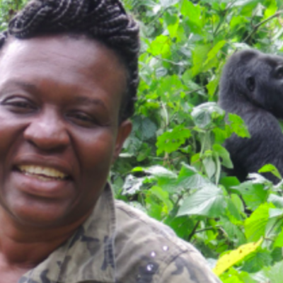 Woman smiling at camera with a mountain gorilla behind her