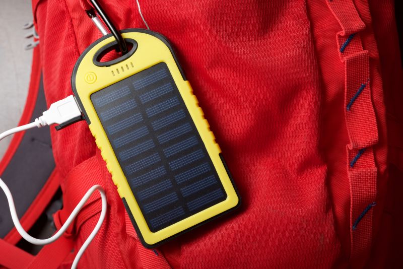 Small yellow portable solar charger attached to a red backpack