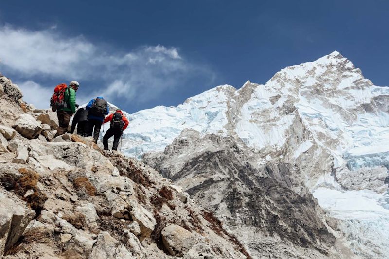 Trekkers climbing a mountain using trekking poles 