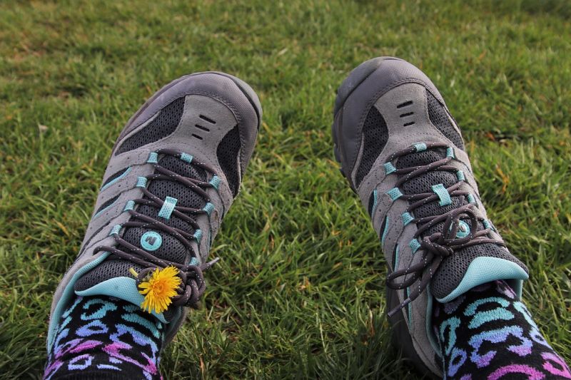 Woman's hiking shoes and colourful socks with a daisy it the left shoelaces