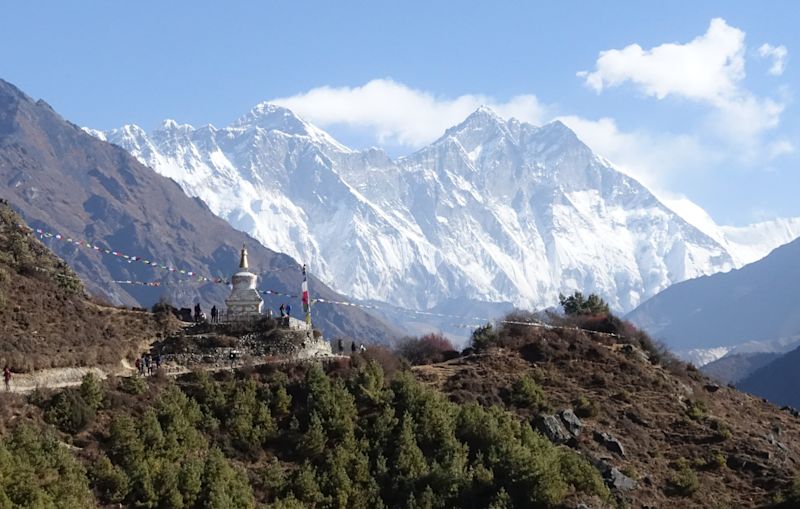 Part of the Everest Base Camp trek trail with prayer flags and a gompa on a sunny day