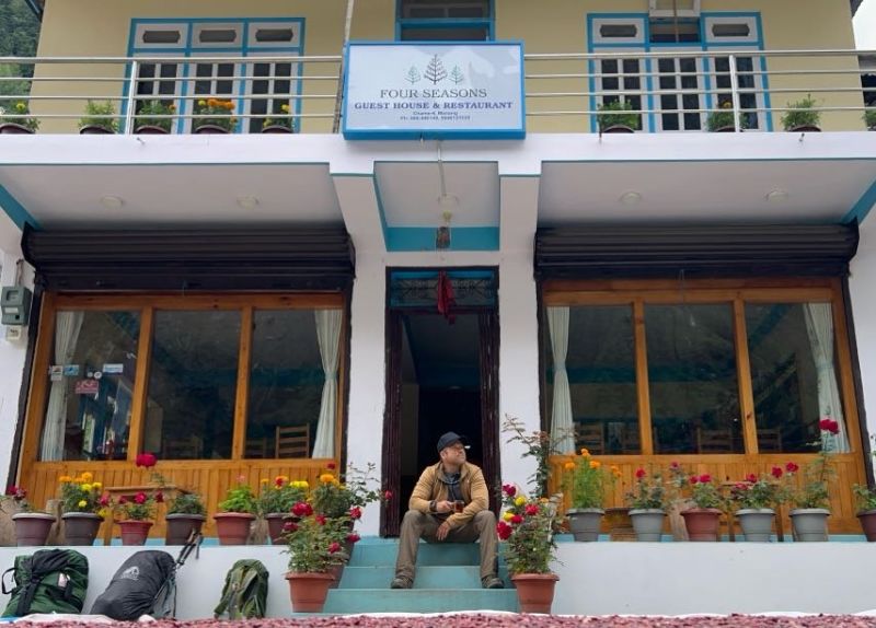 Male trekker sitting on front steps of a teahouse on the Annapurna Circuit