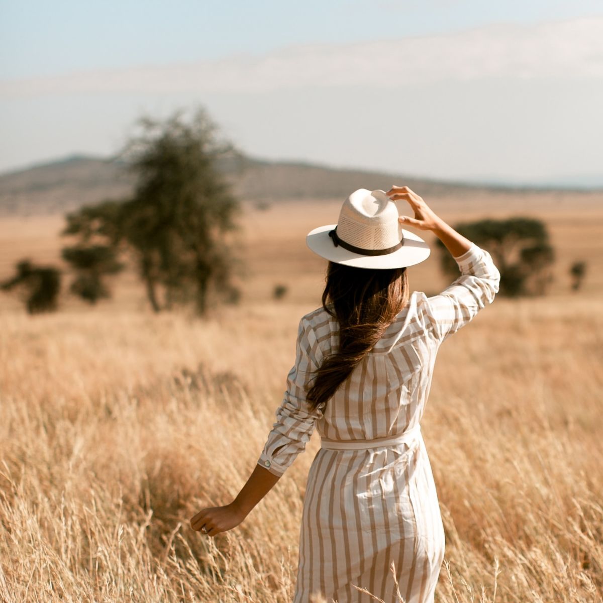 Woman in safari hat in field of grass