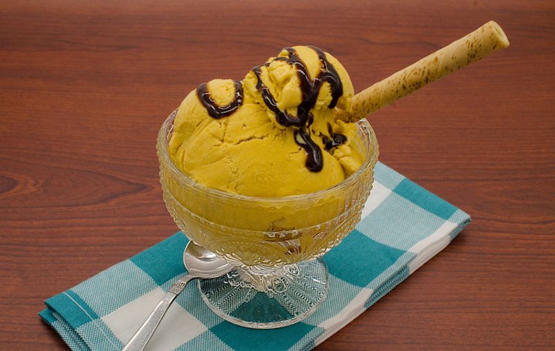  Small glass bowl of lucuma ice-cream on a checked napkin on a wood table 