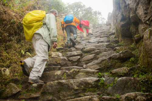 Three hikers on the Inca trail, in the rain and fog near the Puyupatamarca archaeological site, Peru 