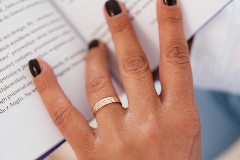 Close up of woman-s hand with ring on wedding finger holding open a book