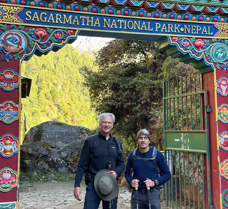Trekkers standing under the Sagarmatha National Park entrance arch on the EBC trek