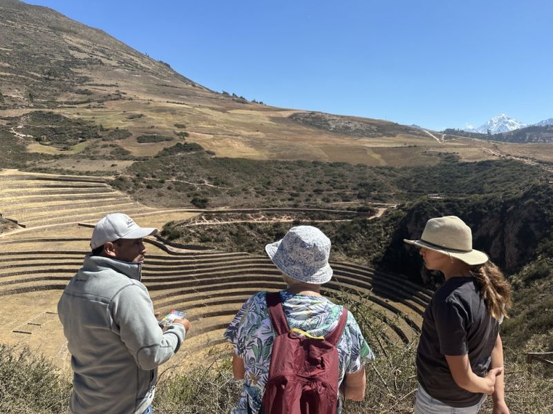 View of three people looking down to Moray ruins, Sacred Valley in winter, Peru