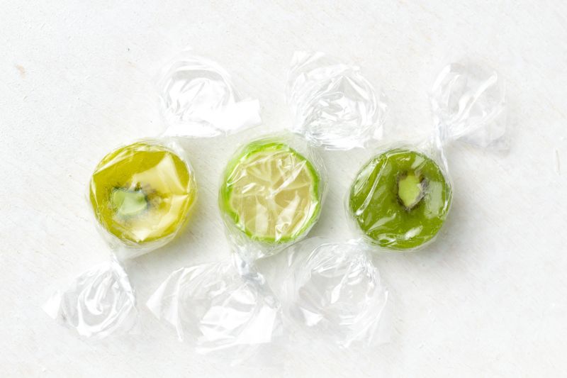 Green, individually wrapped sweets against white background