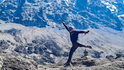 Man leaping in air on Kilimanjaro with Uhuru Peak behind him