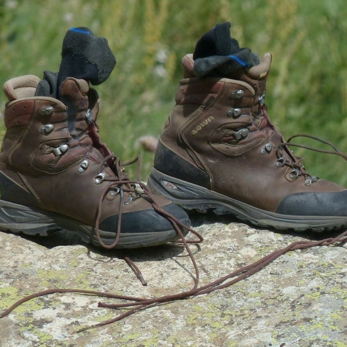 Hiking boot with loose laces and socks on a rock outdoors