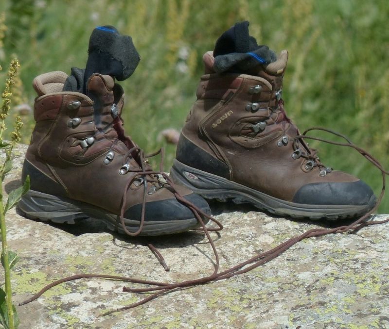 Hiking boot with loose laces and socks on a rock outdoors