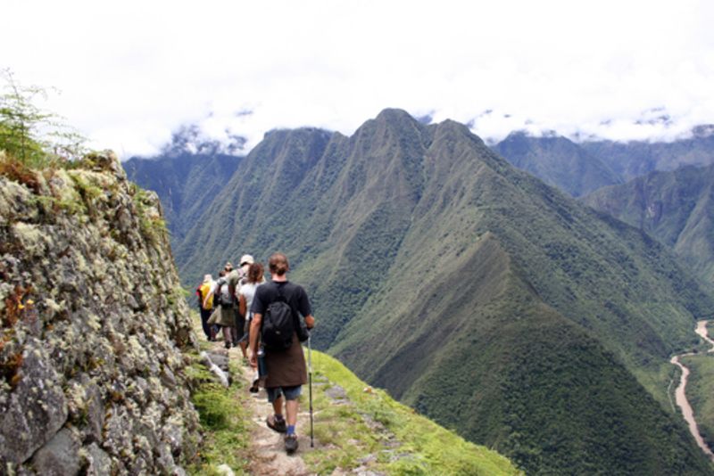 Trekkers on contour path of Inca Trail with river far below, Peru 