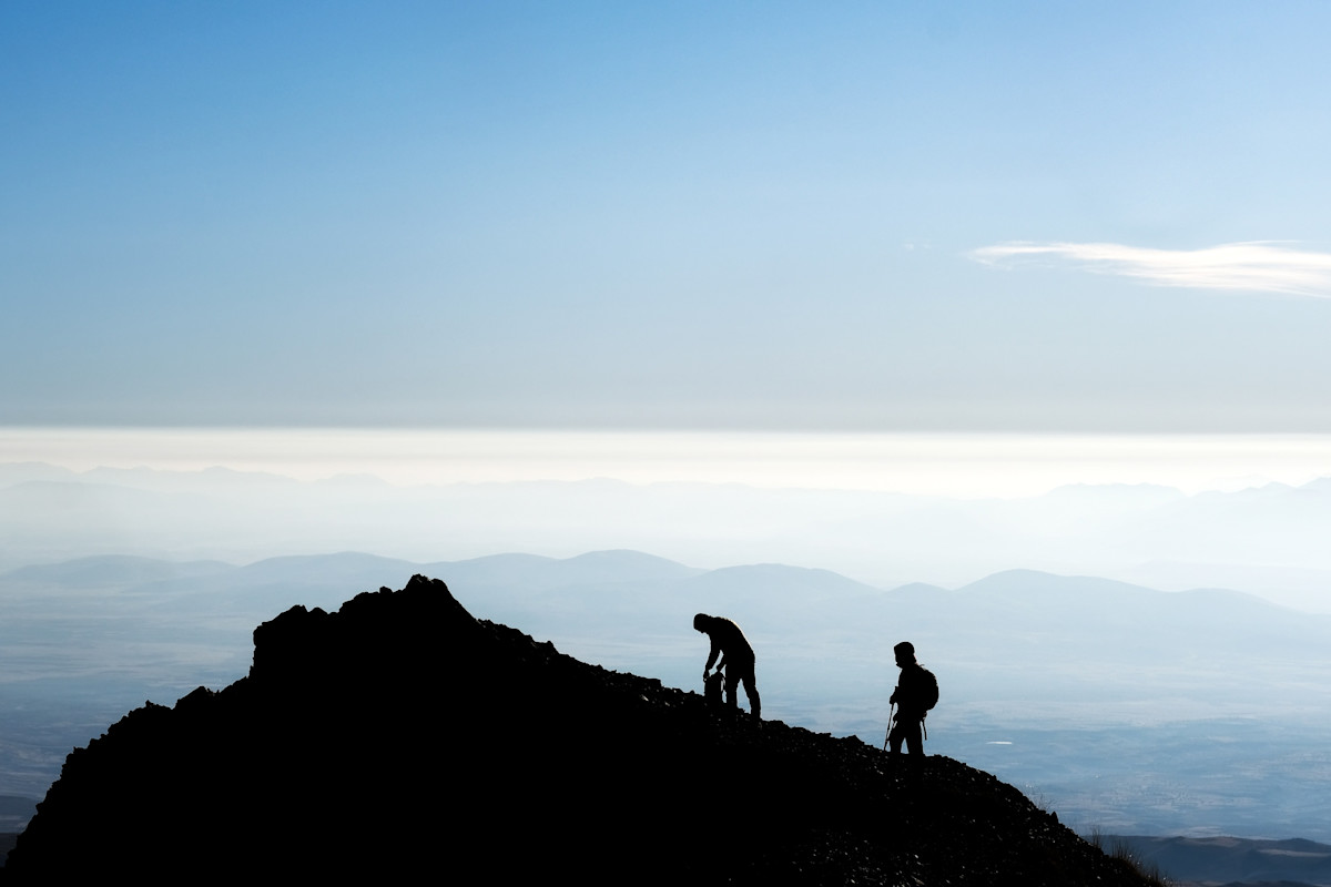 Senderistas en la cima con paisaje abierto y luz suave de montaña