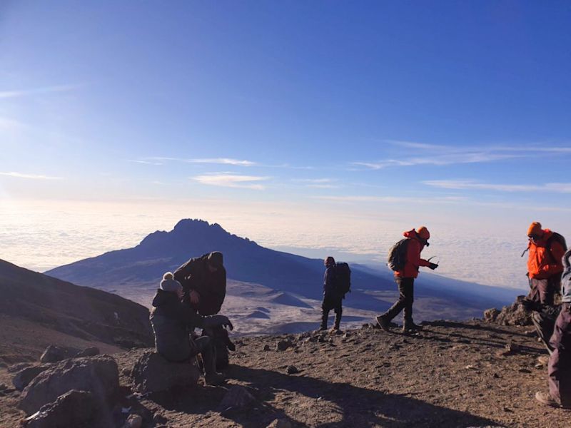 Trekkers resting on Kilimanjaro with clouds in the background