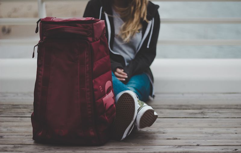 Girl sitting on ground with red tote bag