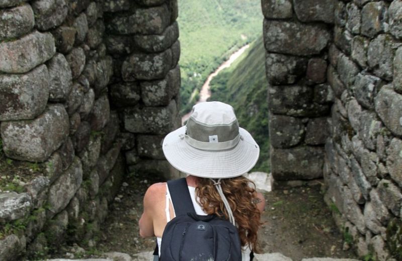 Woman in sunhat seated among ruins of Machu Picchu