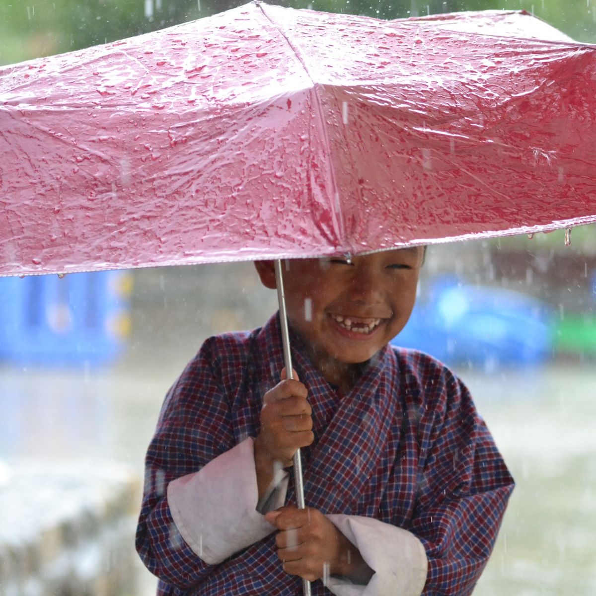 Rain and smiling boy with red umbrella, Bhutan