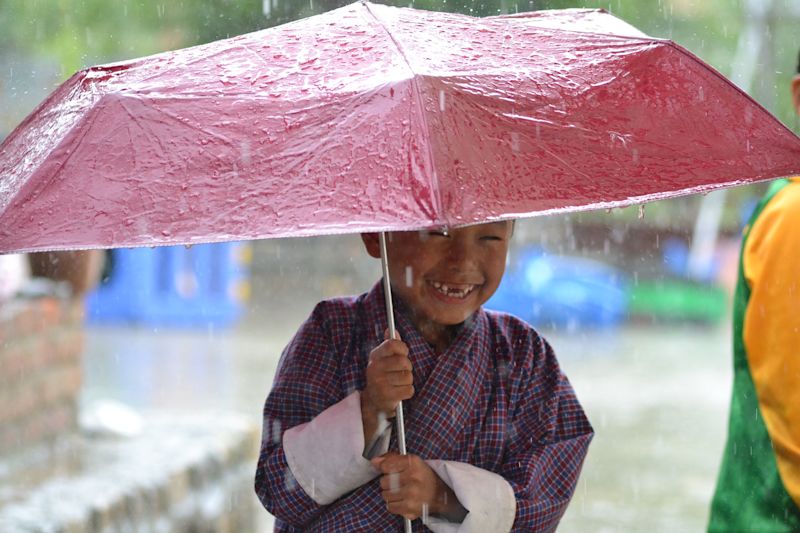 Rain and smiling boy with red umbrella, Bhutan