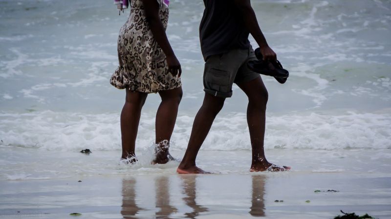 Couple walking barefoot in surf in Mombasa