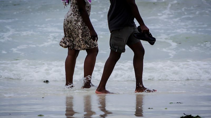 Couple walking barefoot in surf in Mombasa