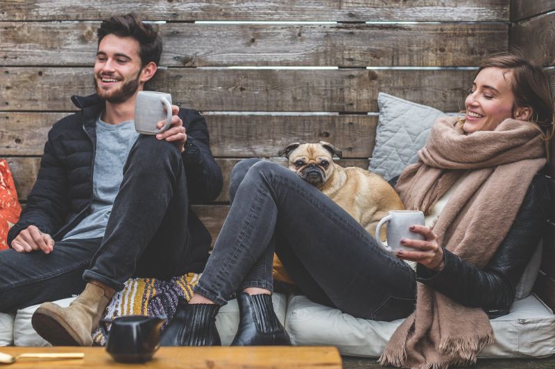 Man woman and dog in cabin cold winter hot drinks happy smiling