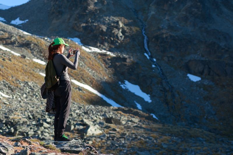 Woman on high-altitude trek taking a photo with a smartphone