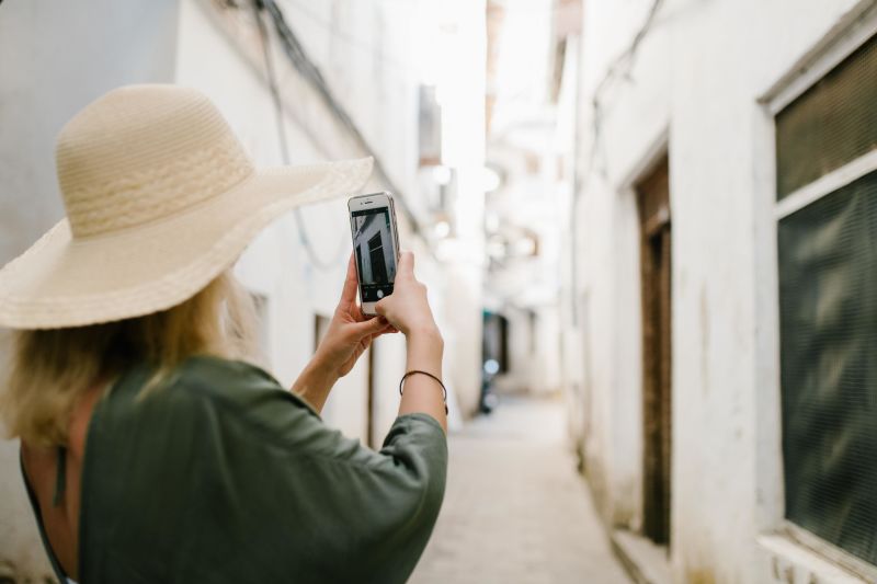 Tourist in hat taking a photo in an alley 