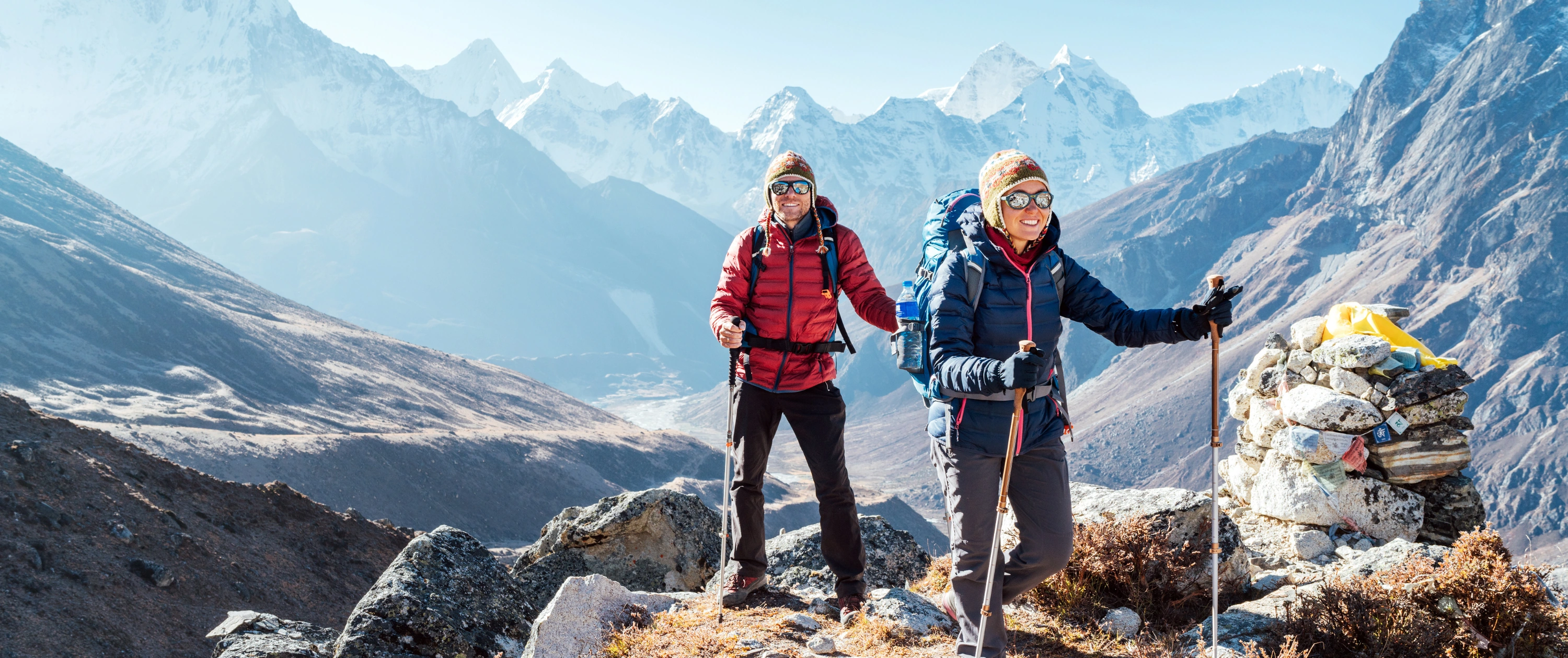 Man and woman trekkers with backpacks and poles on the EBC trek, Nepal.