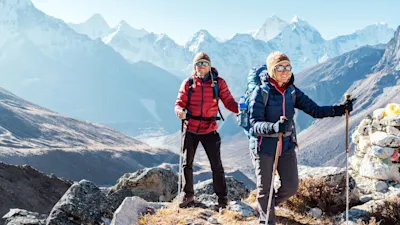 Man and woman trekkers with backpacks and poles on the EBC trek, Nepal.