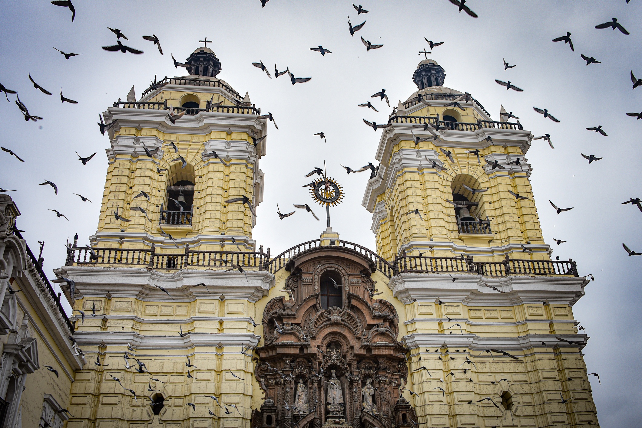 Birds in flight in front of baroque facade of San Francisco Cathedral, Lima, Peru