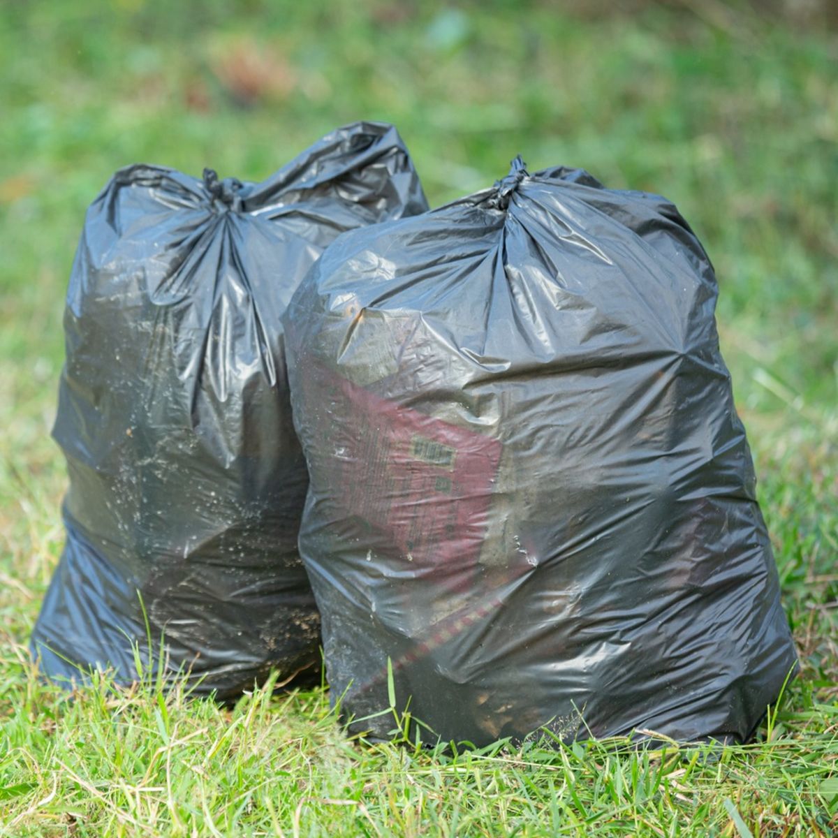 Two black plastic trash bags tied up