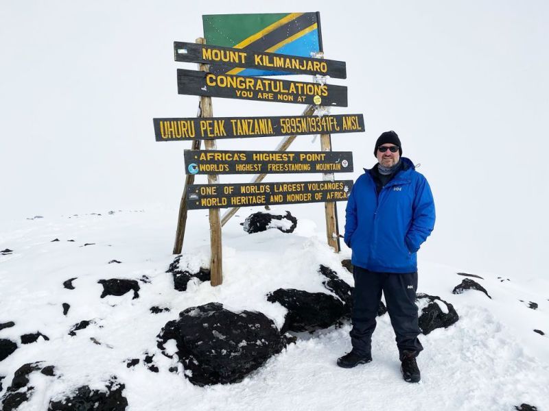 Man Standing Kilimanjaro Summit Sign