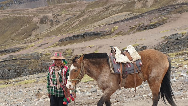 Peruvian man in traditional dress with horse on Rainbow Mountain, Peru