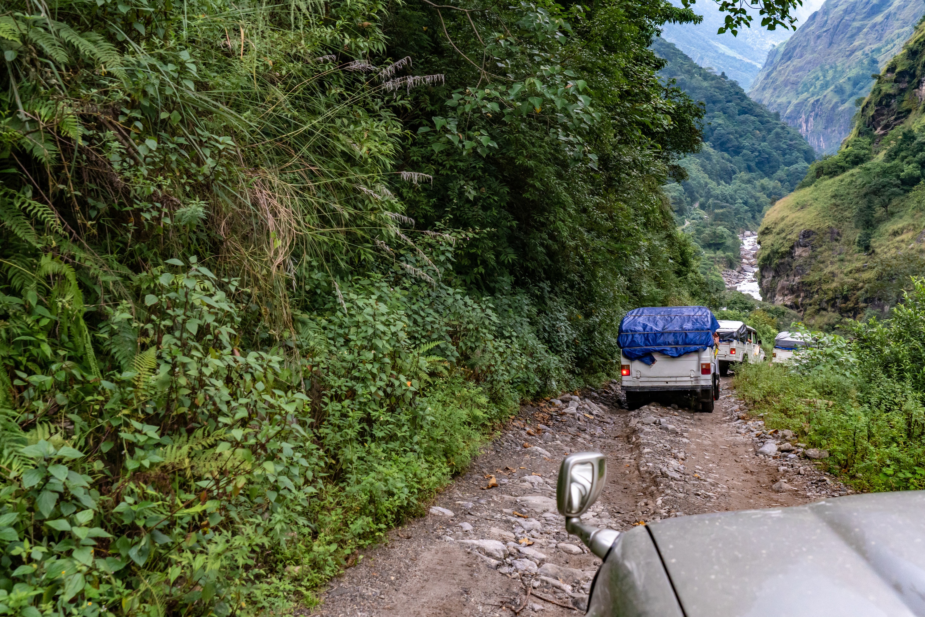 Vehicles on dirt road in lower temperate Annapurna Mountains 