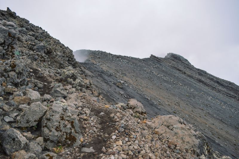 Rock formations and footpath against a foggy background at Mount Meru, Tanzania