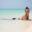 Smiling yound woman lying in shallow blue water on beach in Zanzibar