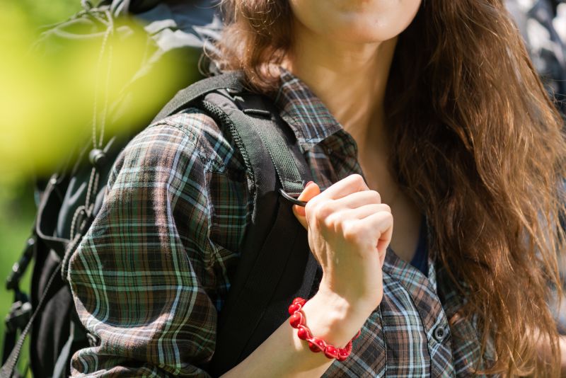 Female hiker in plaid shirt with backpack on, front view, should straps