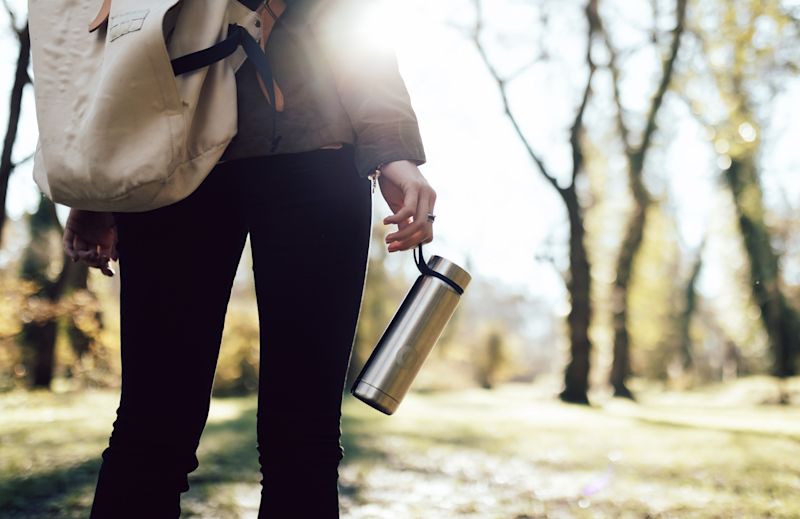 Woman's hand holding a water bottle in the woods