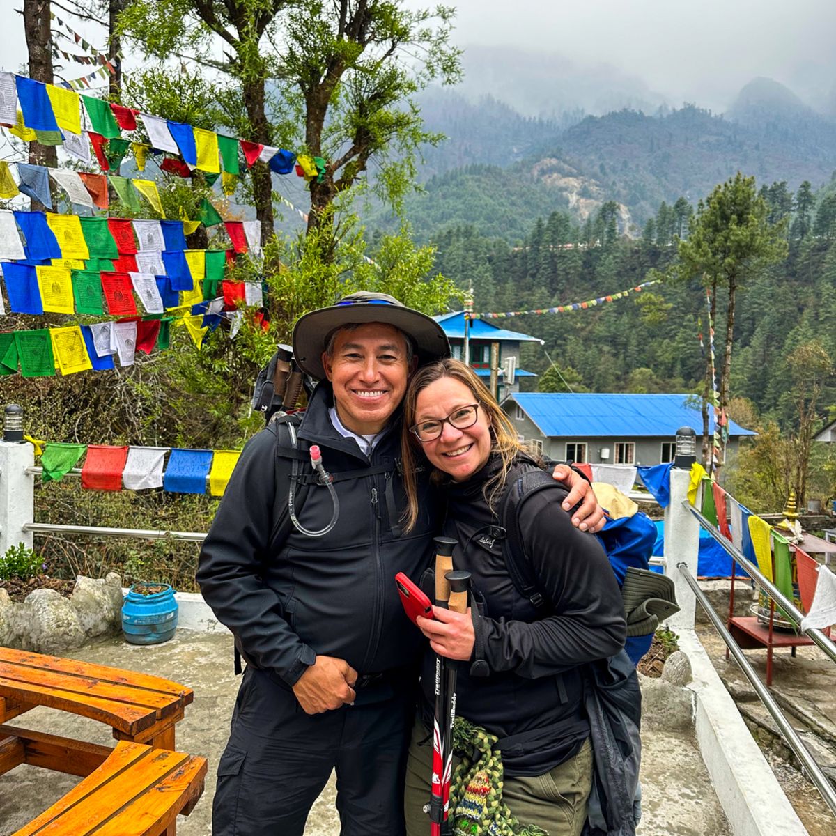 Smiling couple early on EBC trek route, prayer flags, Nepal